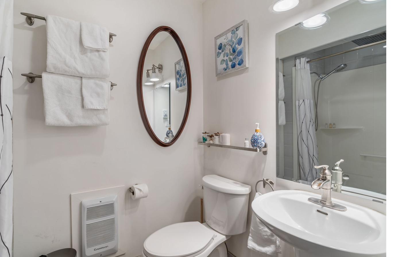 Bright bathroom with stand-up shower, oval mirror, and spa-style décor