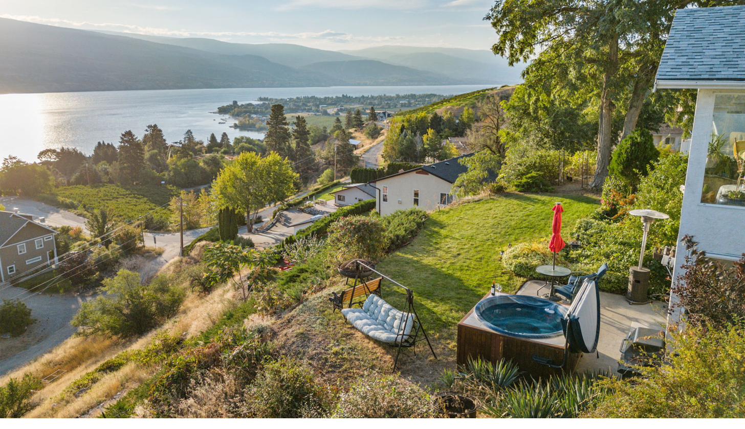 Aerial view looking south-east — hot tub, patio, yard, and Okanagan Lake panorama