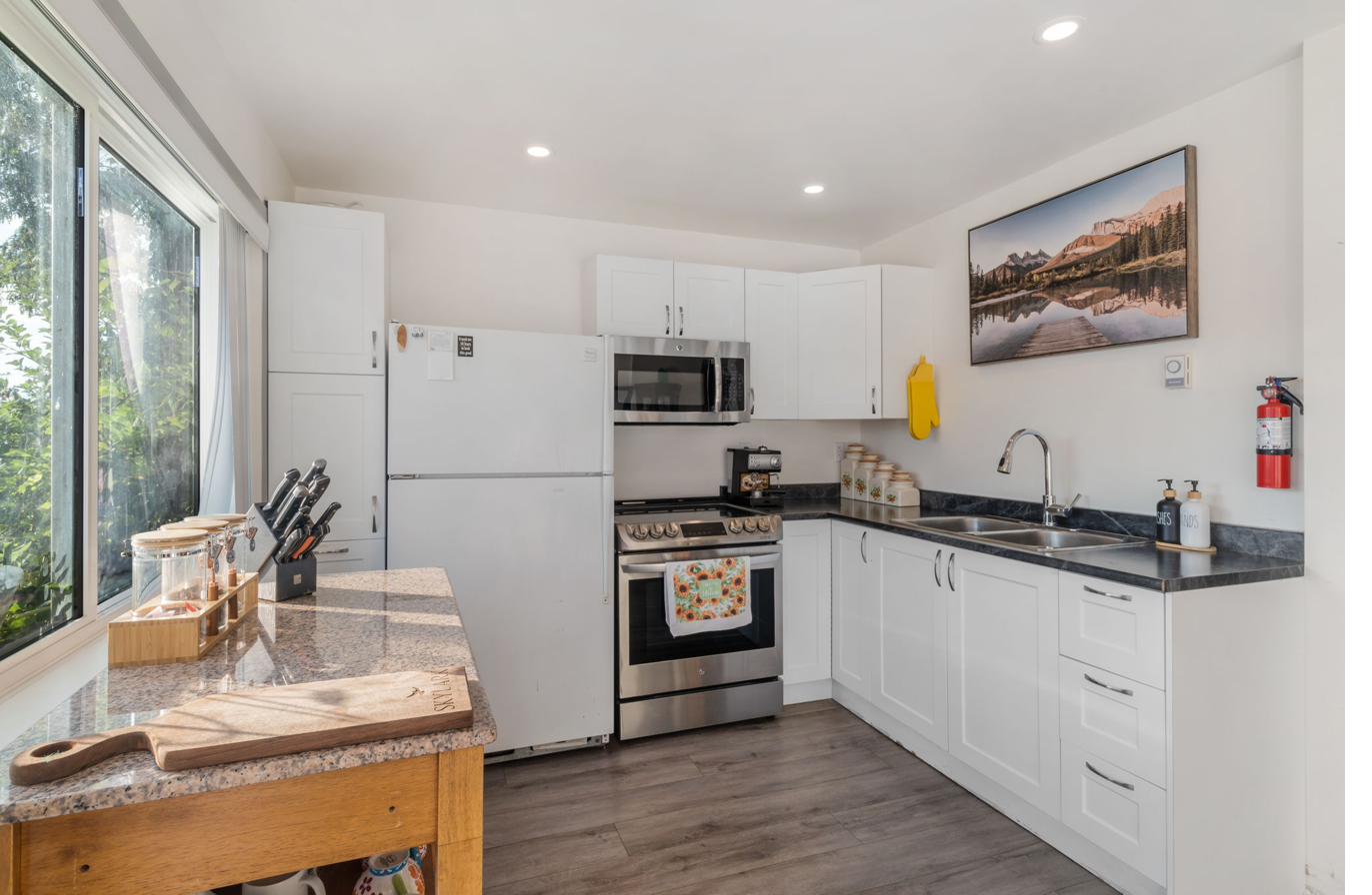 Fully equipped kitchen with stainless appliances, granite counters, and white cabinetry